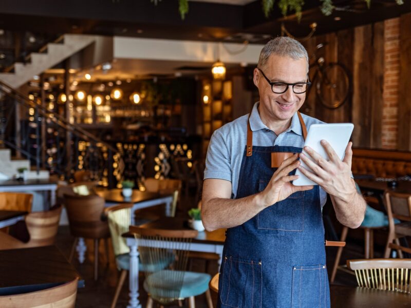 Server in restaurant managing schedules on a tablet.
