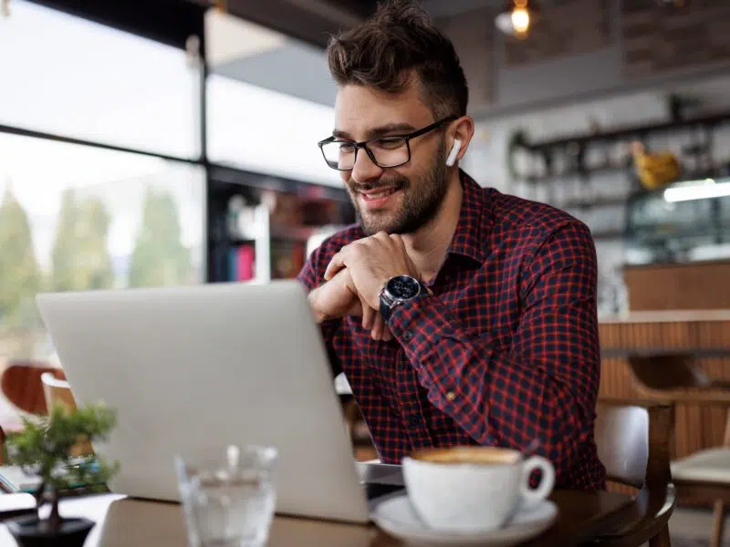 happy man looking at computer and drinking coffee