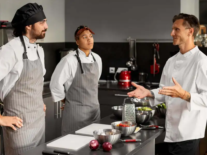 chef talking with cooks in a restaurant kitchen