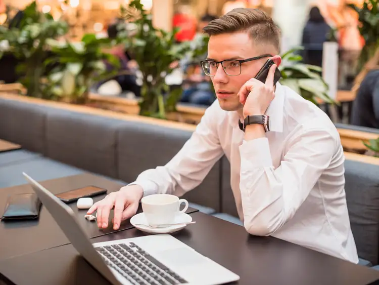 manager on phone while using laptop